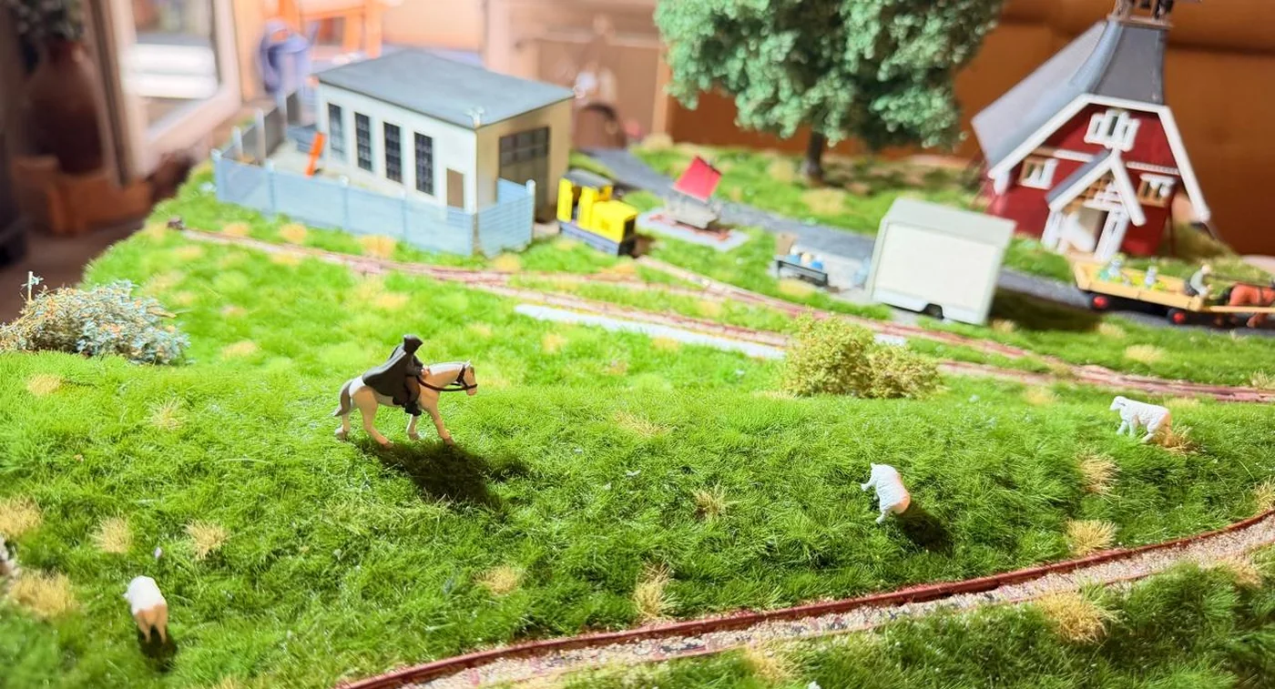 Modellbahn-Landschaft von Busch mit Weide, Gleisen und Gebäuden
